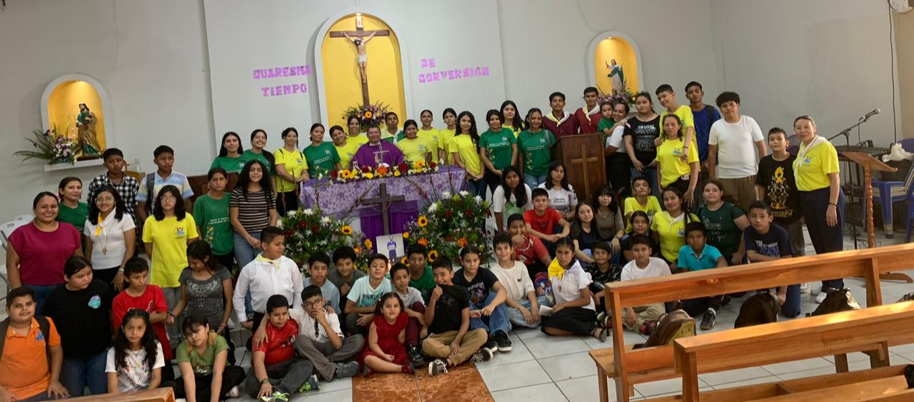 Los niños y asesores de la IAM con el sacerdote frente al altar en Cuaresma